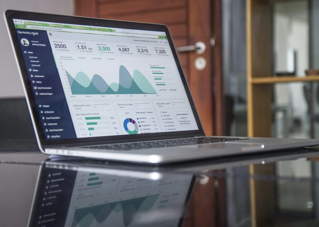 Laptop-Displaying-Website-Analytics-Dashboard Laptop on a glass desk showing website analytics graphs and metrics.